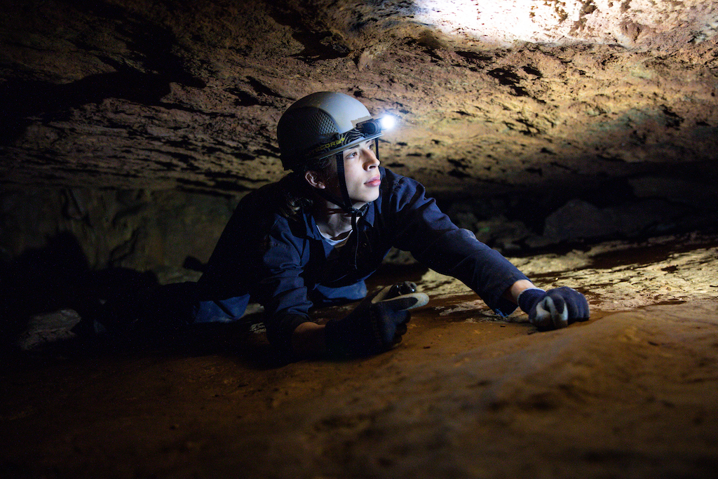 Man crawling in a cave at Grand Caverns.